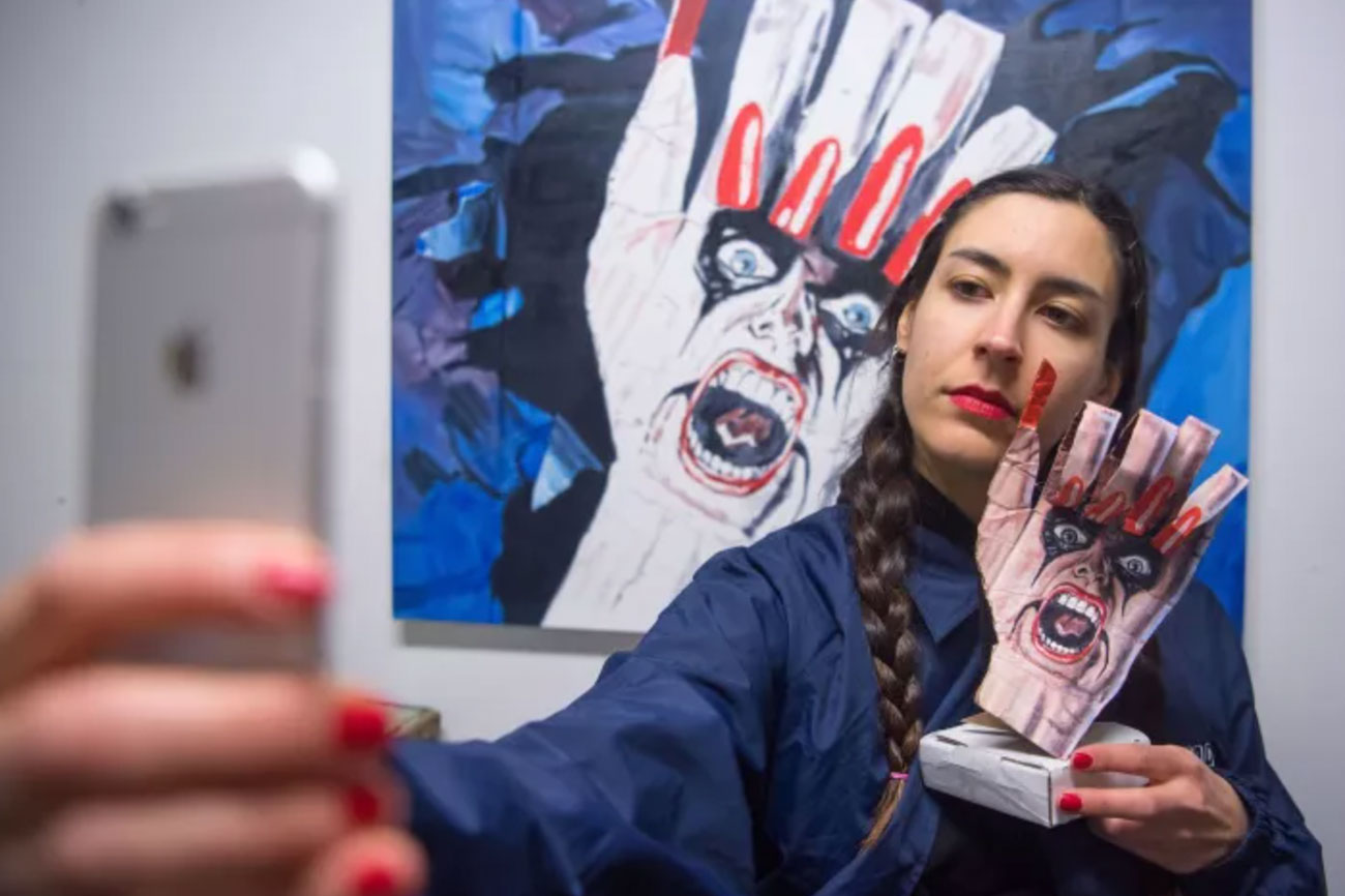 Bay Area artist Laura Rokas snaps an Instagram selfie in front of her artwork at her studio in San Francisco. (Josh Edelson / For The Times)